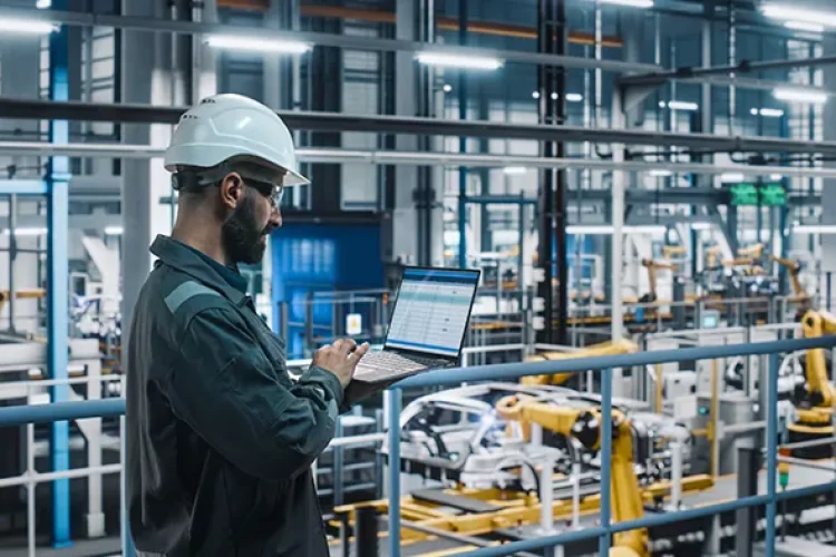 Arbeiter steht mit Laptop in Fabrik