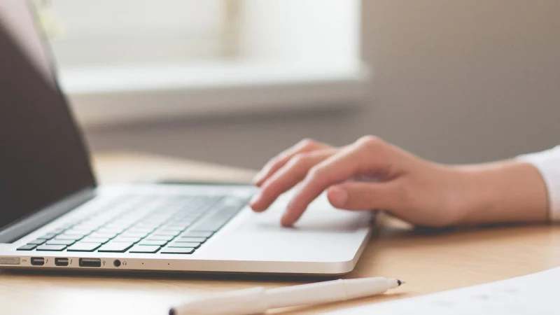 Hand tippt auf einem Laptop