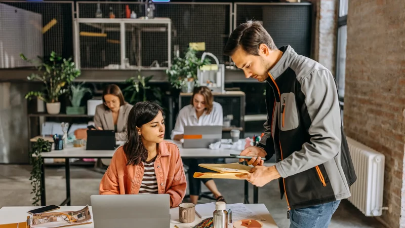 Zusteller liefert Post an Frau im Büro
