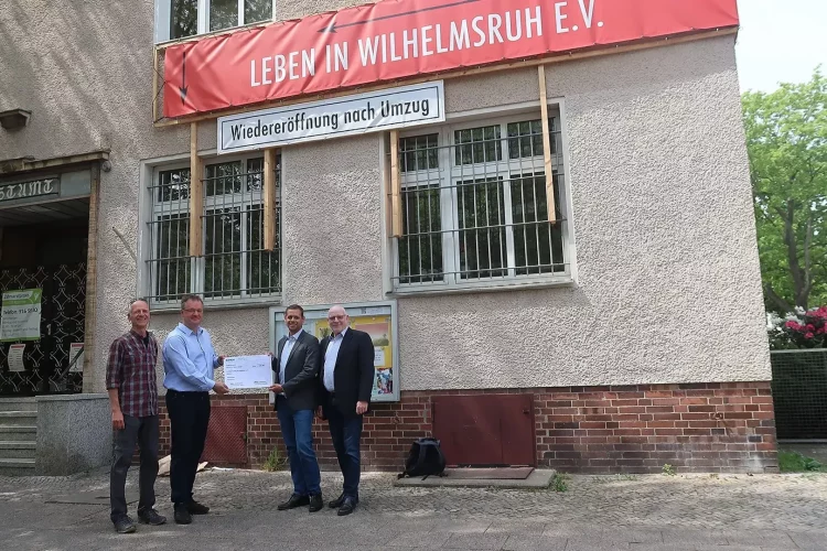 Vier Männer stehen zusammen und zeigen eine Check